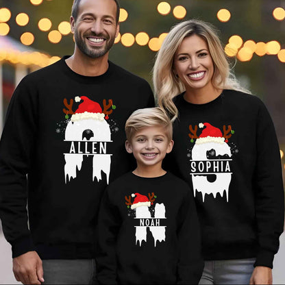 Family of three wearing black sweatshirts with Santa Claus designs and names.